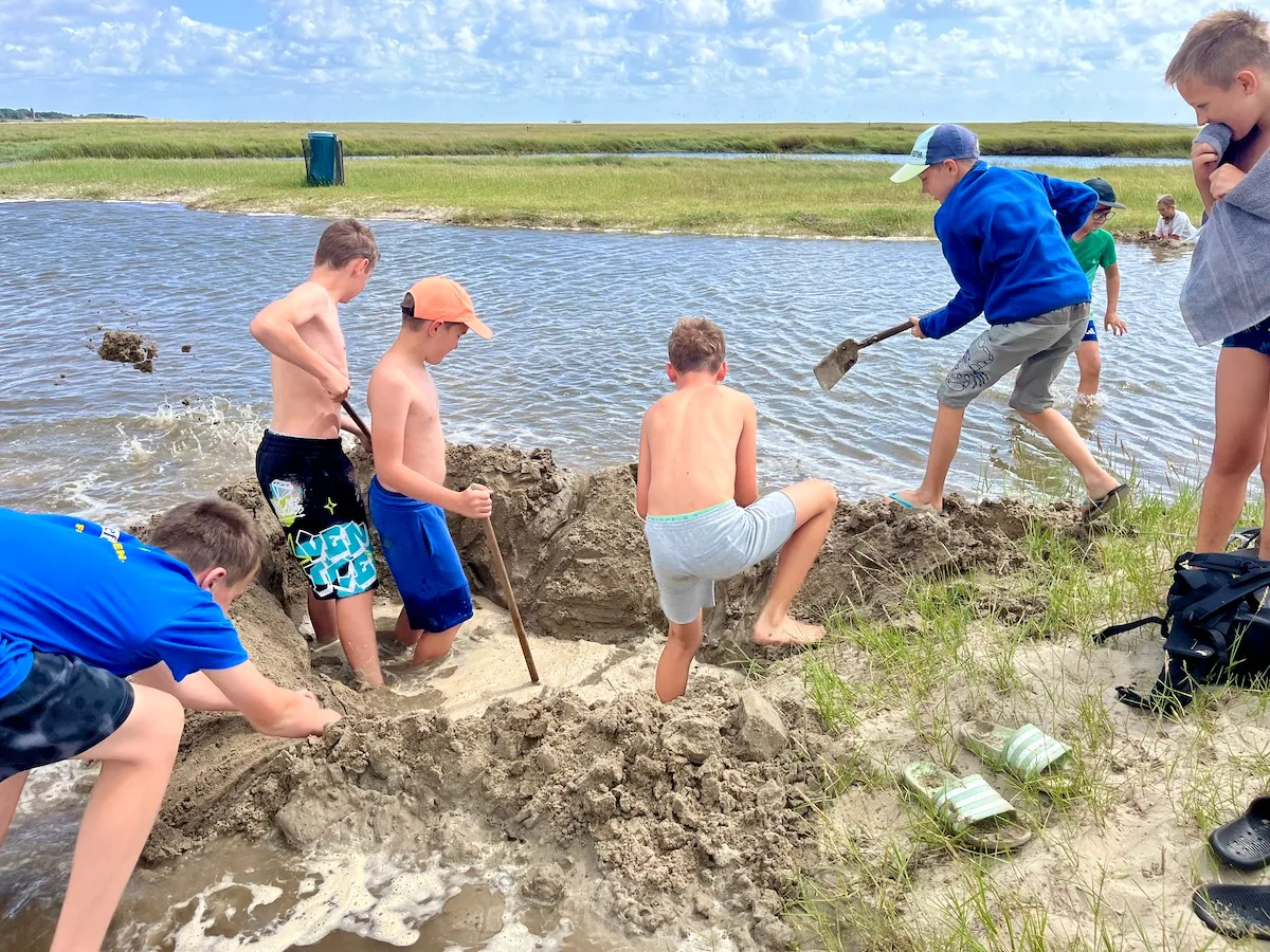 Kinder bauen Sandburg am Wasser