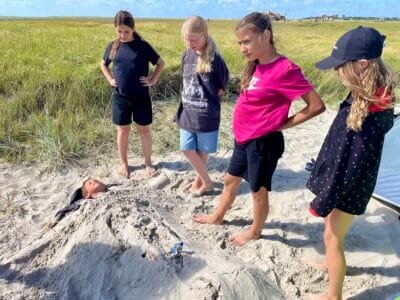 Mädchen beobachten im Sand vergrabene Person.