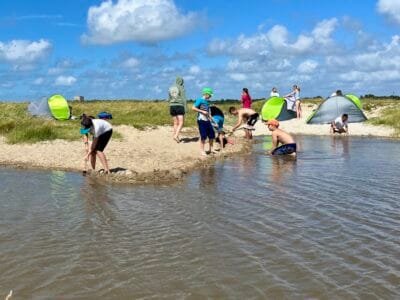 Kinder spielen am Strand mit Wasser.