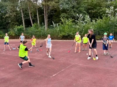 Kinder spielen Hockey im Freien