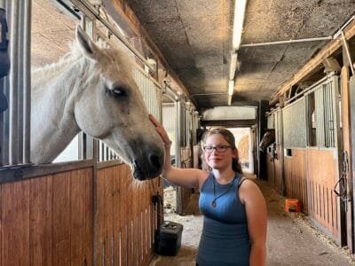 Mädchen streichelt ein weißes Pferd