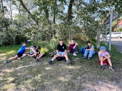 Sechs Kinder sitzen im Schatten.