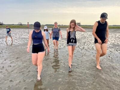 Menschen gehen barfuß am Strand.