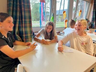 Drei Mädchen spielen am Tisch.