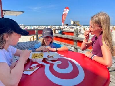 Drei Kinder essen am Strand.