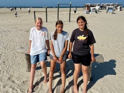 Drei Mädchen am Strand stehen.