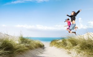 Kinder springen über Dünen am Strand